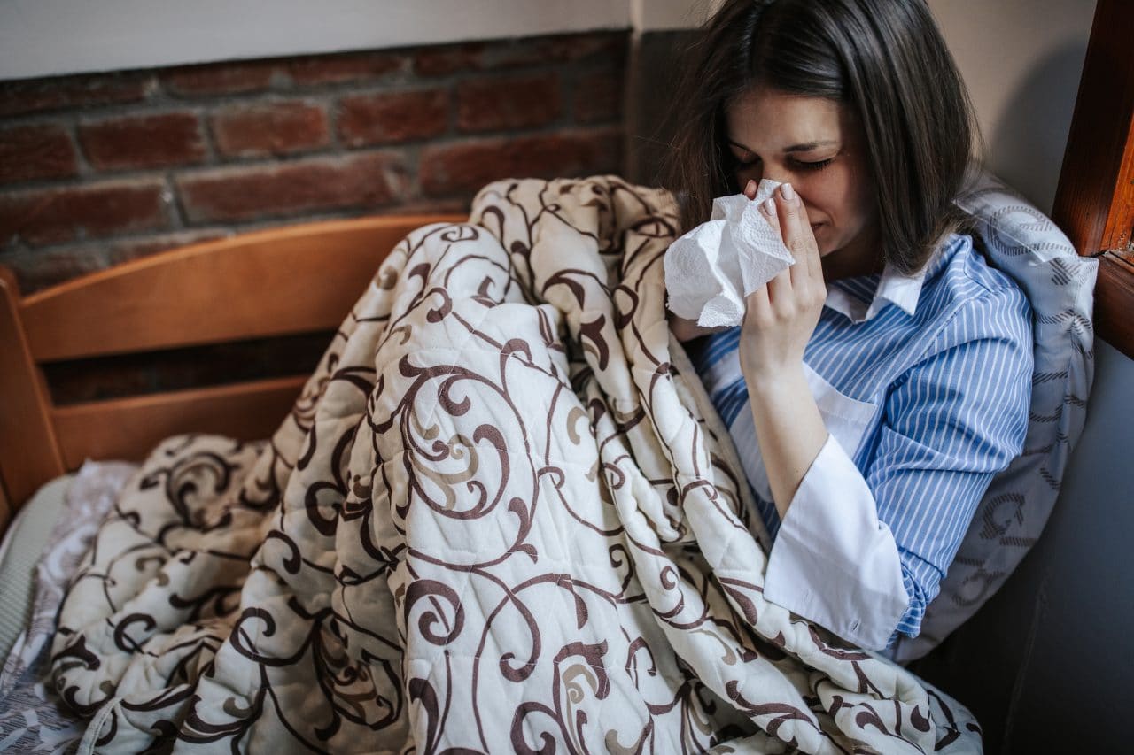 Woman with stuffy nose from allergies sitting on a couch.