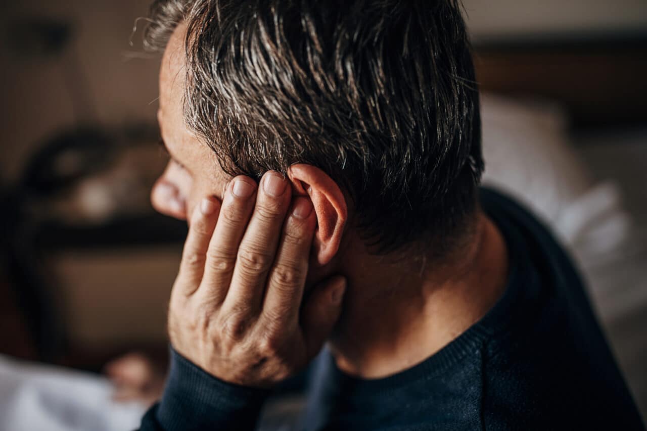 Man with an earache putting his hand to his ear.