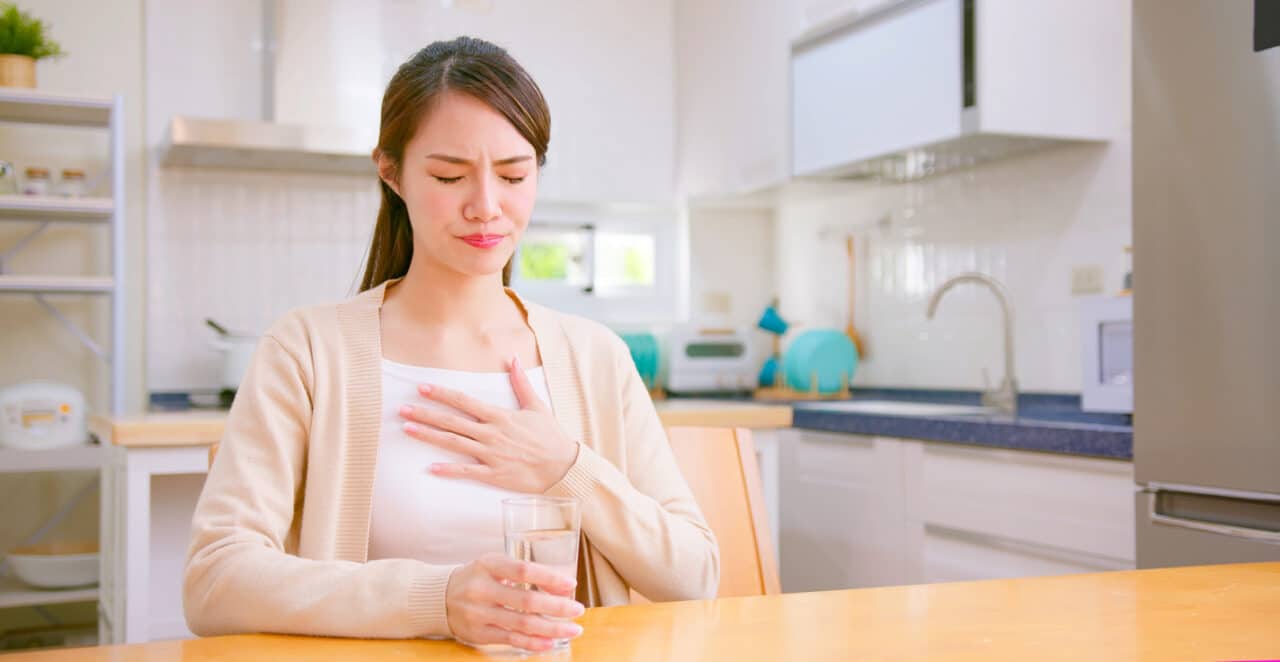 Woman suffering from acid reflux putting her hand to her chest.