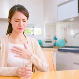 Woman suffering from acid reflux putting her hand to her chest.