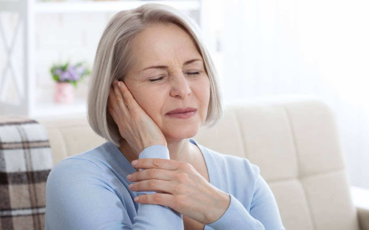 Woman with ear pain pressing her hand against her ear.