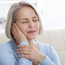 Woman with ear pain pressing her hand against her ear.