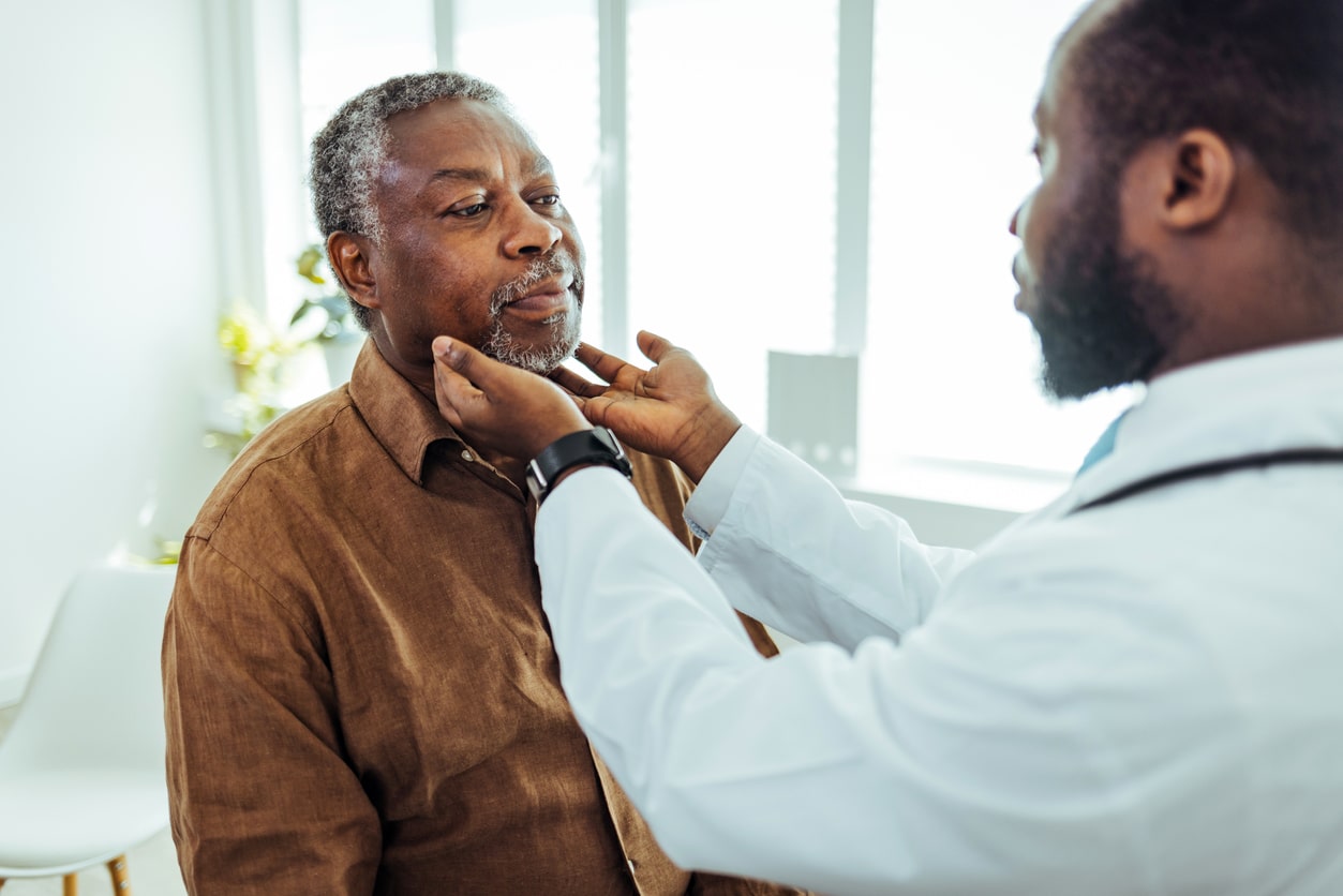 Doctor performing a throat exam on an older man.