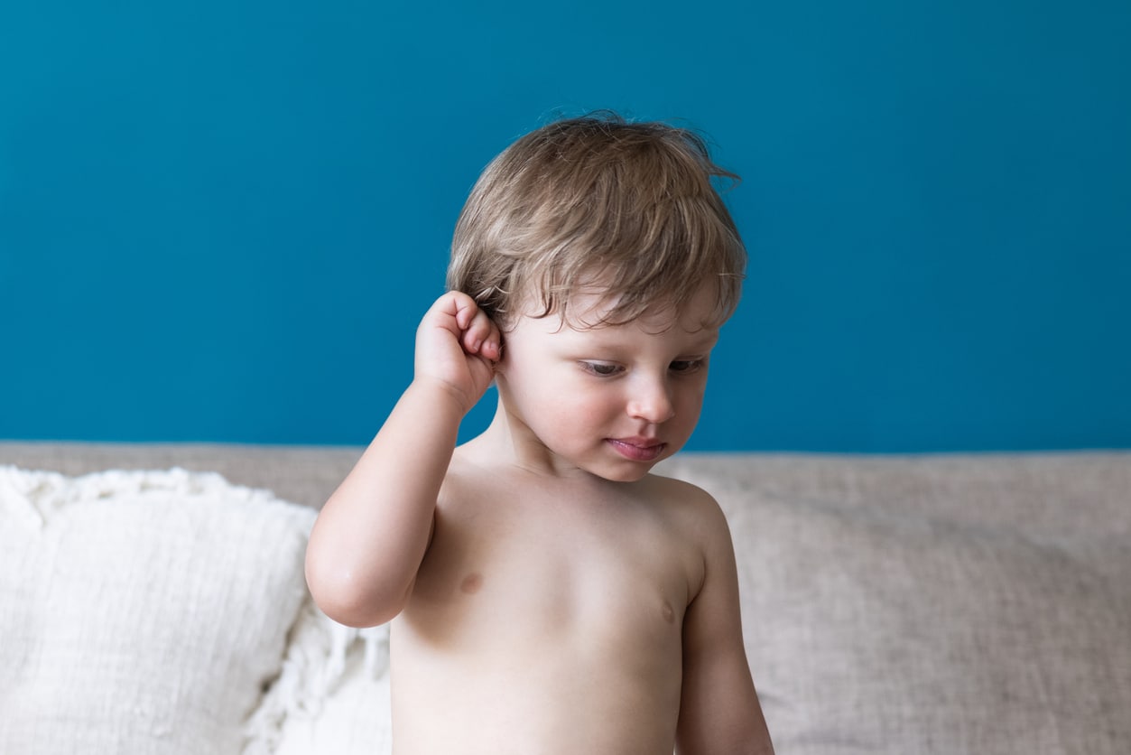 Young boy holds his ear