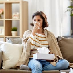 Woman on a couch blowing her nose