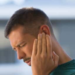 Man with ear pain holds ear