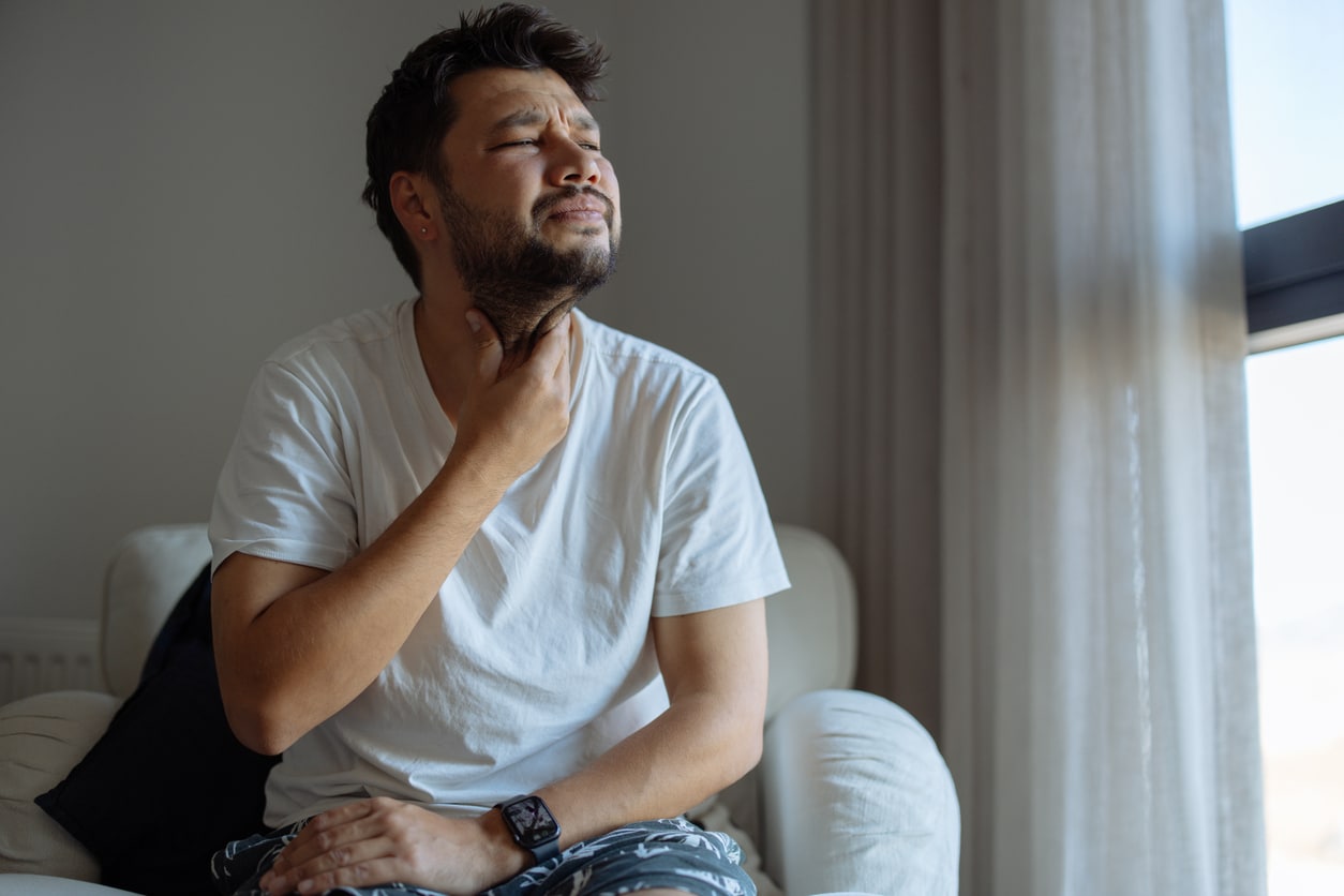 Man holding his sore throat.