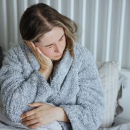 Woman with ear pain holds ear